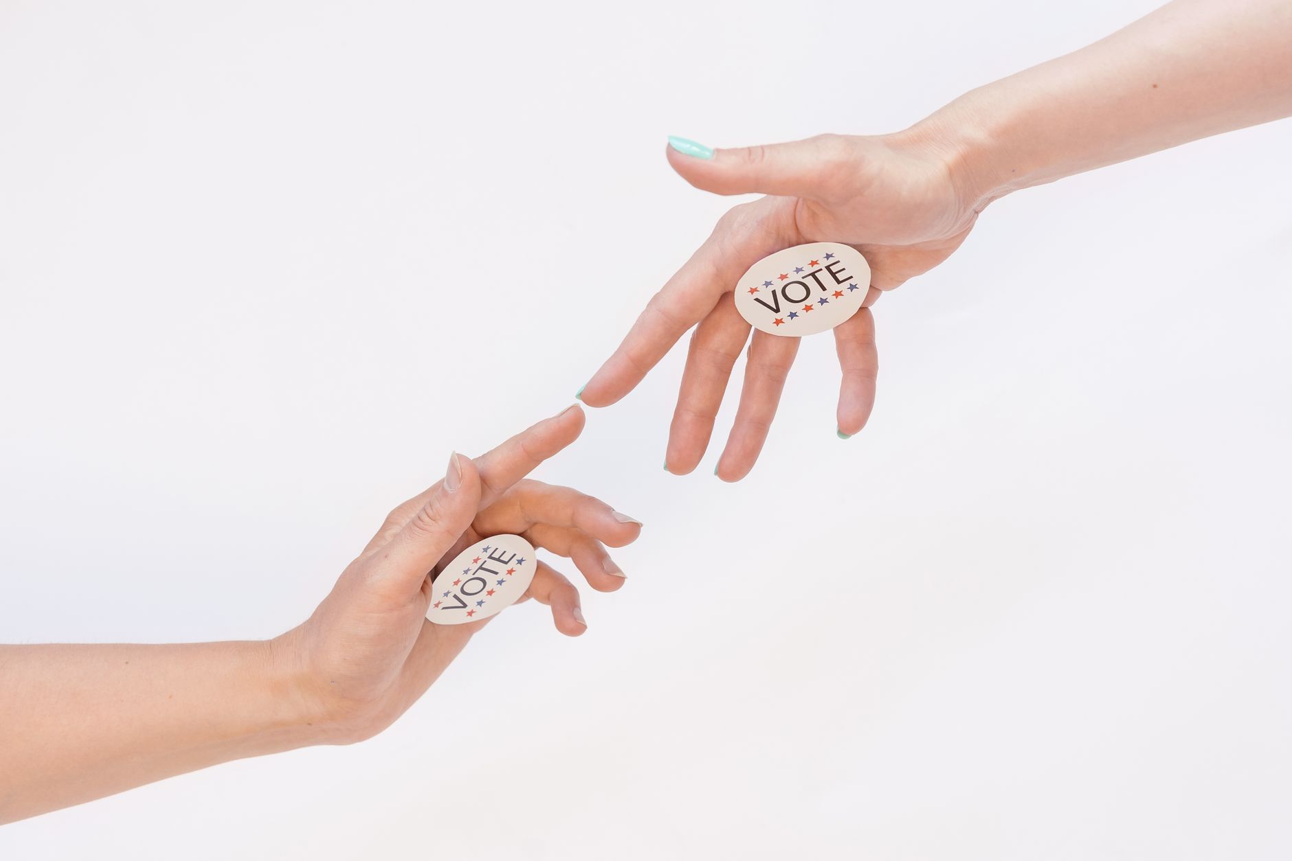 Two hands reaching with vote stickers, symbolizing participation and democracy in elections.